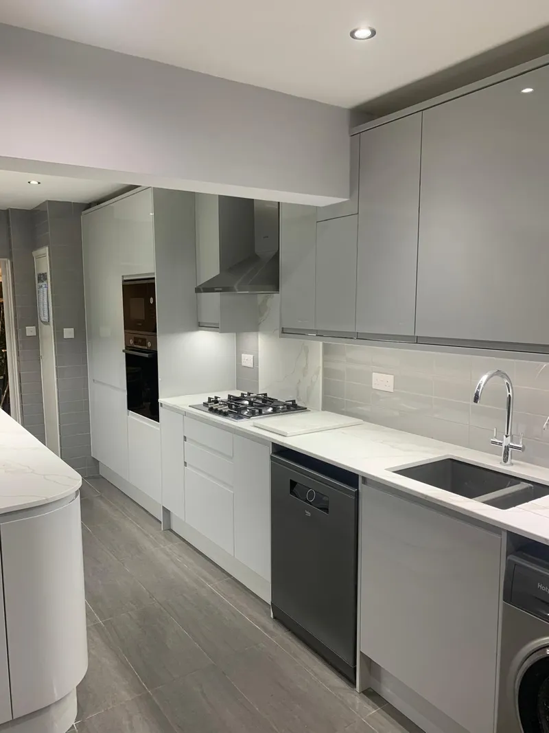 Grey gloss galley kitchen with integrated appliances.