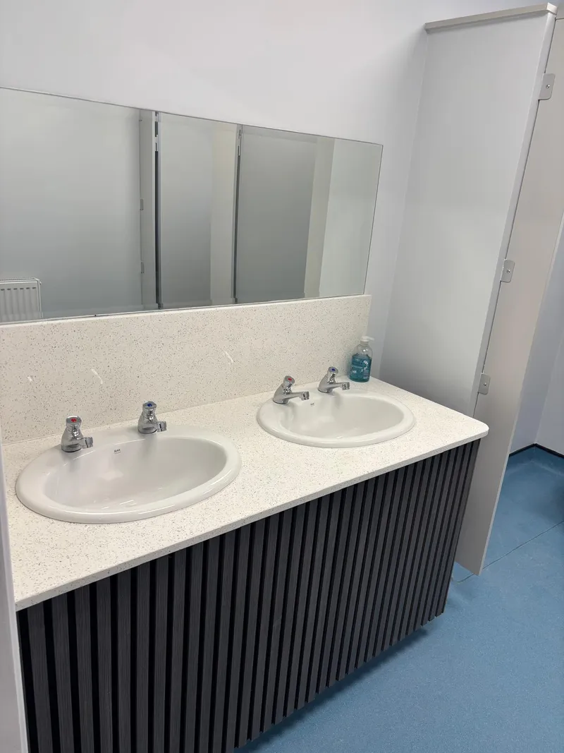 Commercial washroom with a twin vanity unit and fluted panelling.